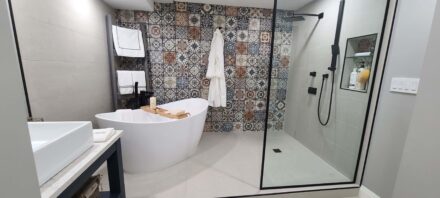 Kitchener bathroom renovation, sleek freestanding tub, shower fixtures, and a bold patterned tile accent wall.